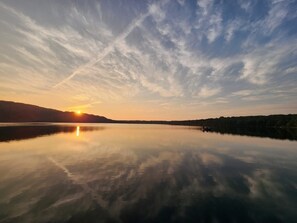Een kalm meer bij zonsondergang met een heldere lucht en verre bergen.