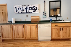 Una cocina con armarios de madera, un lavavajillas blanco y un cartel que dice 'The Lynn Family Lake House'.
