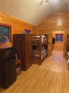 Een compacte hut met een kitchenette, stapelbedden en een kleine eethoek.