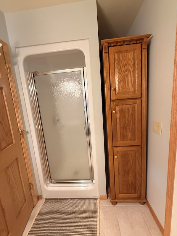Una habitación con ducha, un armario de madera y un tapete con textura.