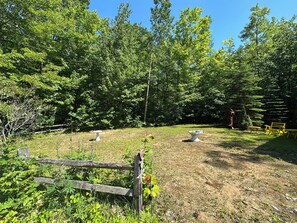 A rustic outdoor area with a wooden fence, a birdbath, and a bench.