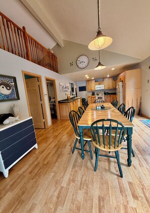 A spacious kitchen with wooden cabinets, a dining table, and chairs.