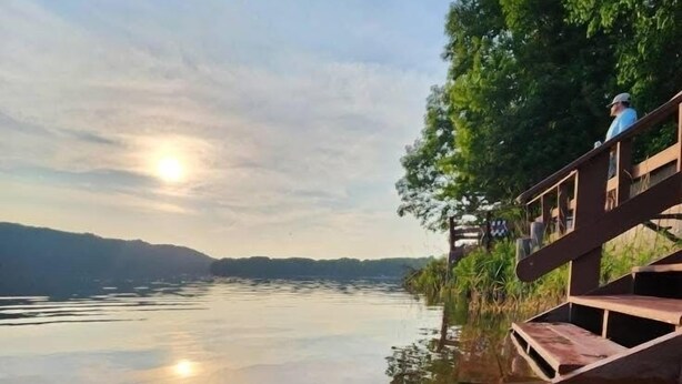 A calm lake with a wooden dock extending into the water, surrounded by trees and a clear sky. - Fall Lakefront Escape on Monocle Lake with Private Dock + Bunkhouse (Brimley)