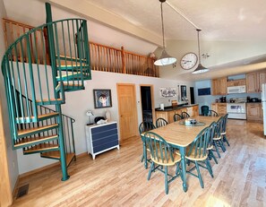 A spacious kitchen with a wooden table and chairs, a spiral staircase, and a dining area.