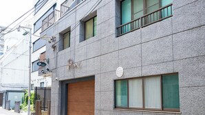 A multi-story building with a stone facade, a wooden garage door, and multiple windows. - PrinetzShinjuku4F (Tokyo)
