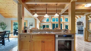 Una cocina de madera con una isla central, horno empotrado e iluminación colgante.