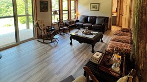 A spacious living room with a wooden ceiling, a sofa, a rocking chair, and a coffee table.