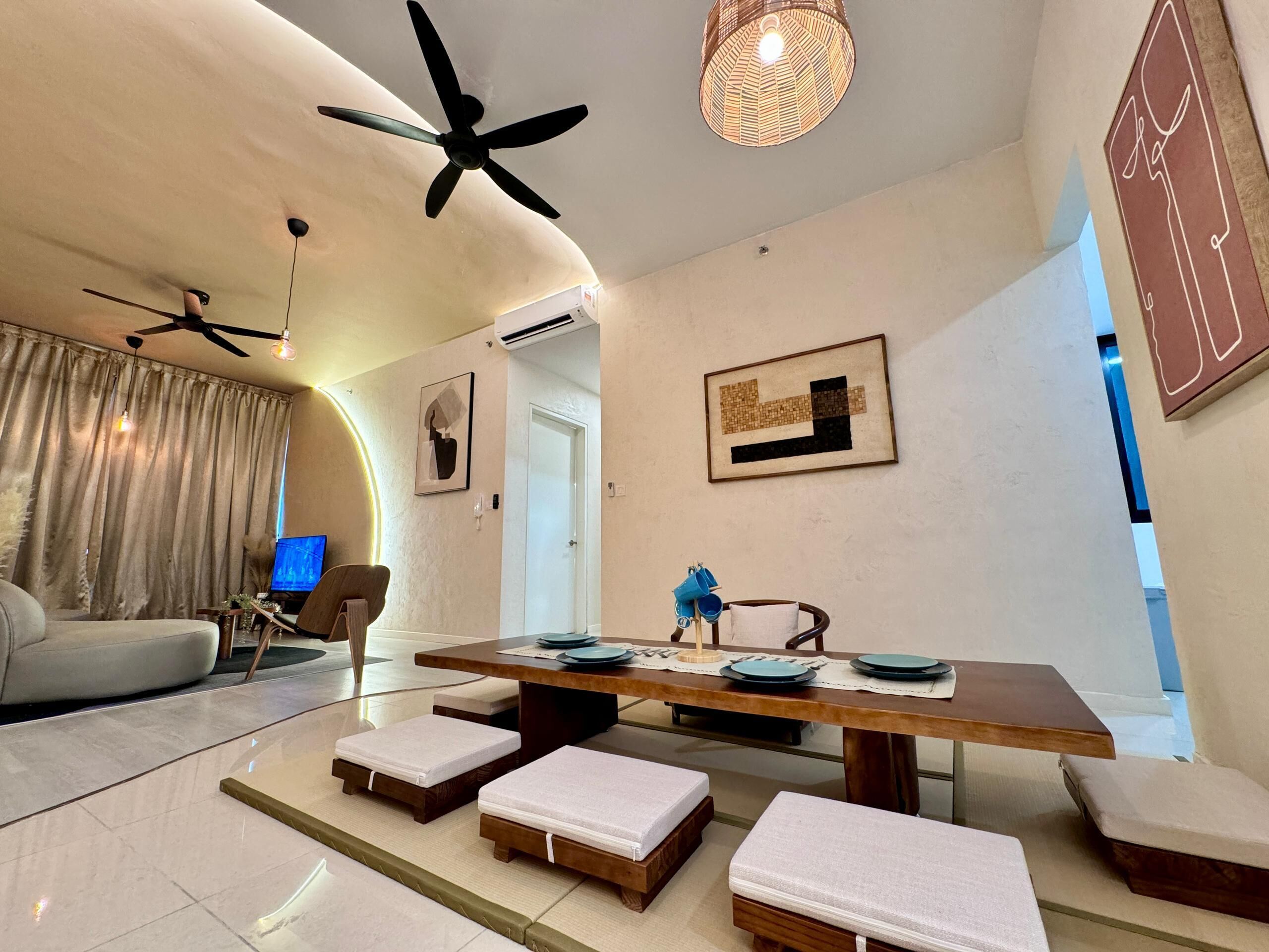 Una sala de estar moderna con una gran mesa de comedor, dos sofás, un ventilador de techo y un equipo de aire acondicionado instalado en la pared.