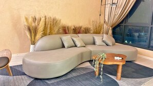 Una sala de estar moderna con un sofá modular curvo, una pequeña mesa de centro de madera y una lámpara de pie alta.