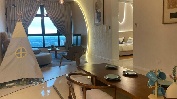 Una sala de estar moderna con un ventanal grande, un comedor con mesa y sillas de madera, y una zona de estar acogedora con un sofá y una butaca.