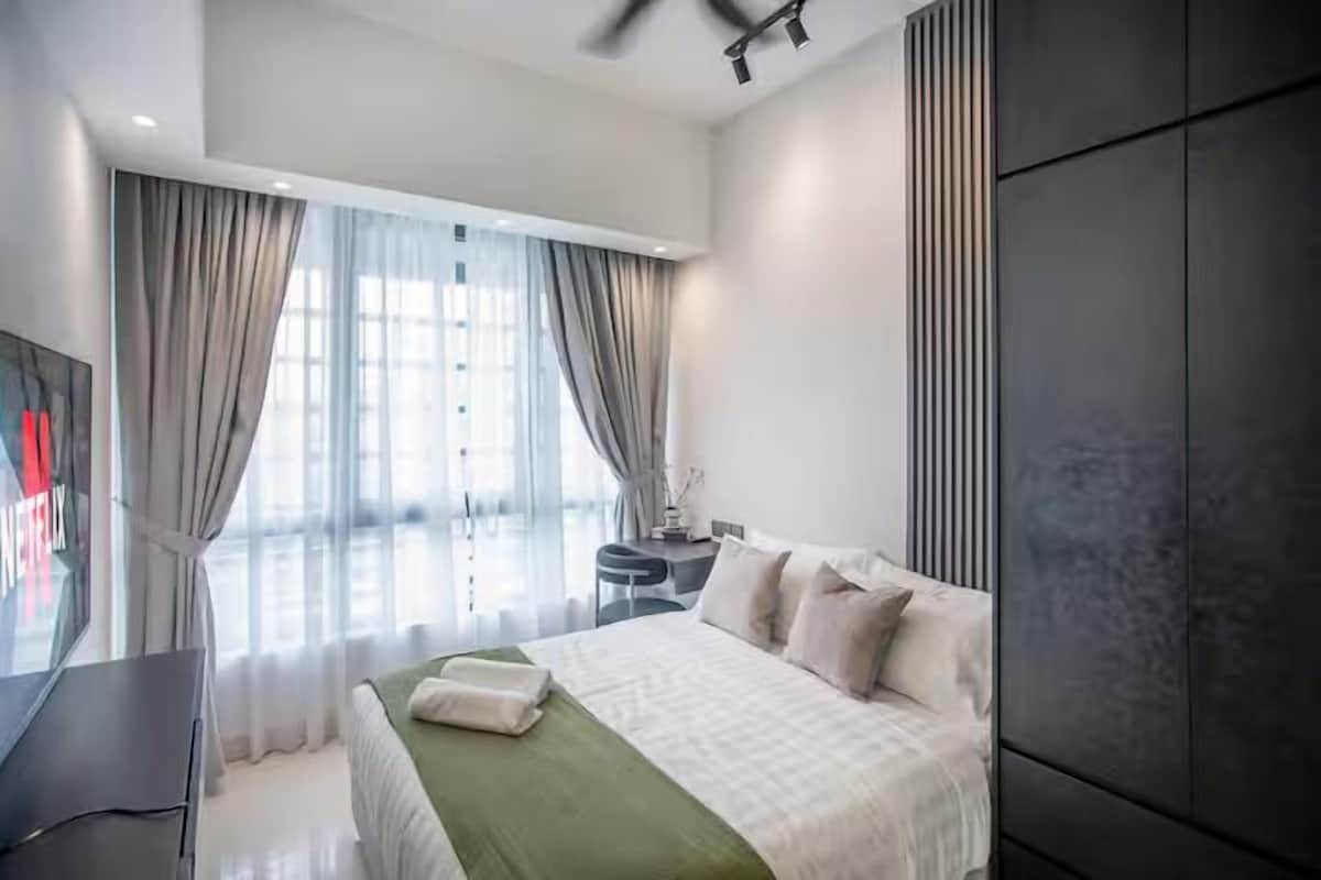 Una habitación de hotel moderna con una cama grande, un escritorio y un televisor.