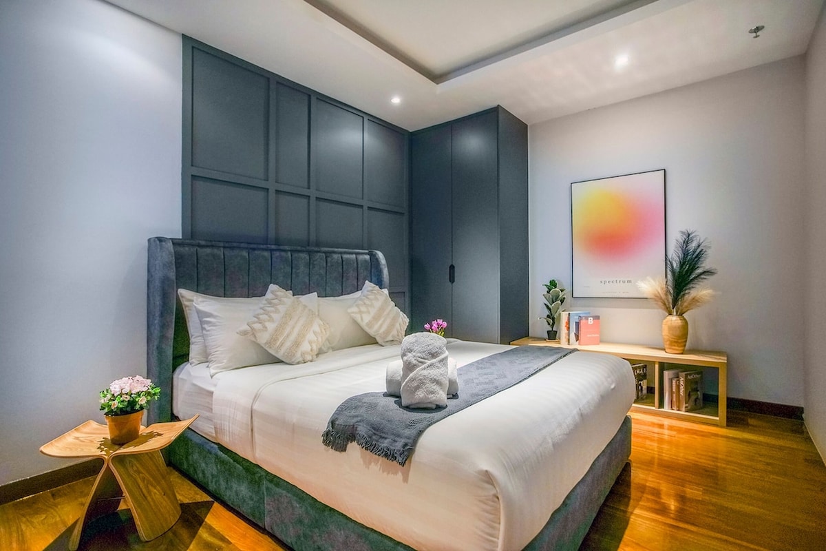 Un dormitorio moderno con una cama grande, una mesita de noche con lámpara y una obra de arte en la pared.