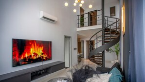 Ein modernes Wohnzimmer mit einem Flachbildfernseher, der einen Kamin, eine Treppe und einen Balkon zeigt.