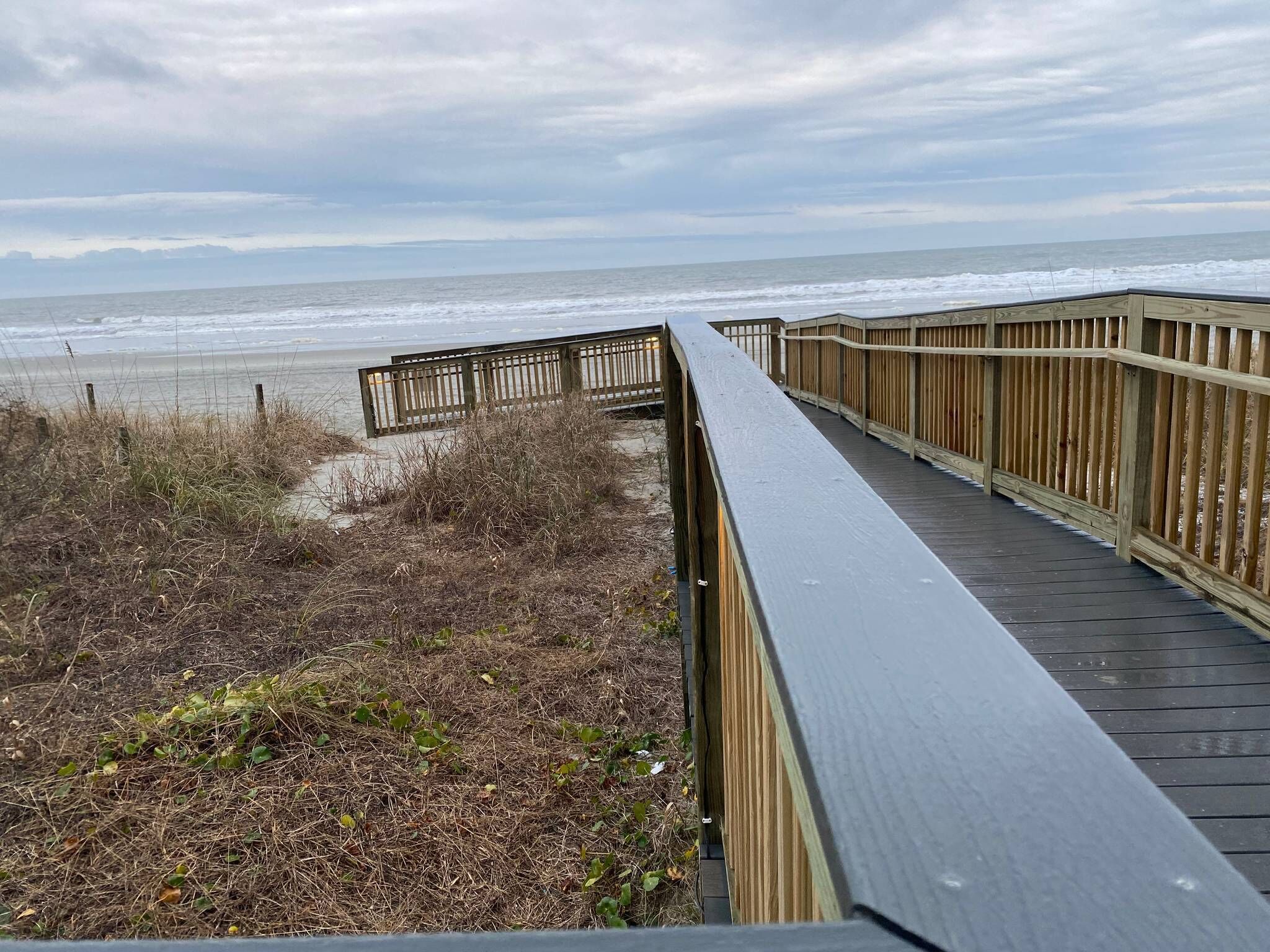 Una pasarela de madera que lleva a la playa, con vista al océano.