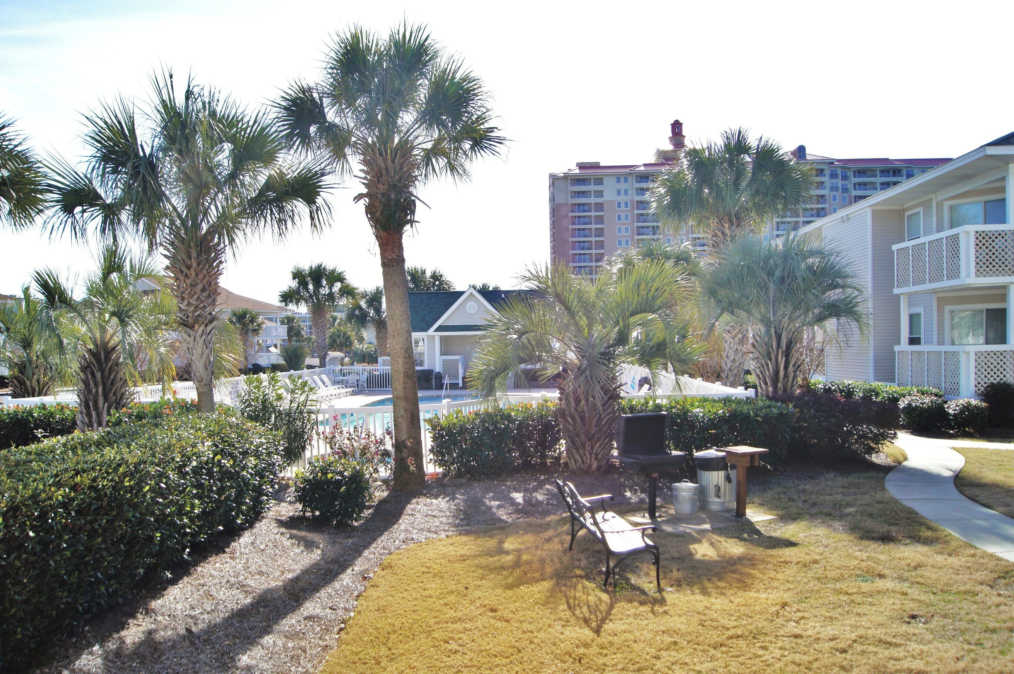 A resort area with palm trees, a pool, and a building with balconies.