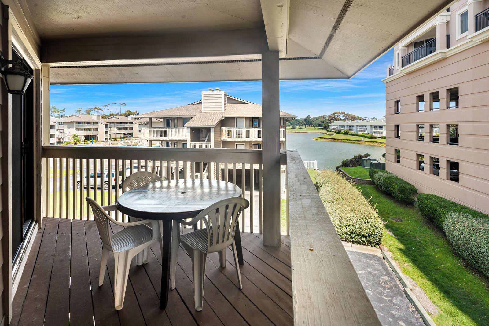 Een balkon met een tafel en stoelen, met uitzicht op een rivier en een golfbaan.
