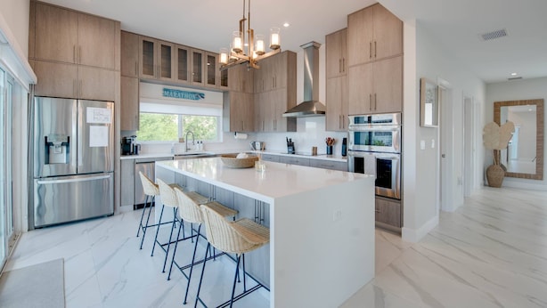 Una cocina moderna con una isla grande, electrodomésticos de acero inoxidable y armarios de madera.