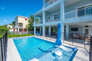 Una piscina con una sombrilla azul, rodeada por una valla blanca.