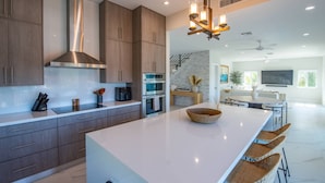 Una cocina moderna con electrodomésticos de acero inoxidable, una isla grande y un comedor con taburetes de bar.