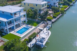 Un hotel de varios pisos con piscina, un barco amarrado y vista al agua.