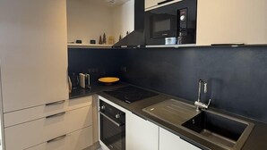Una cocina moderna con encimera negra, pileta de acero inoxidable y electrodomésticos integrados.