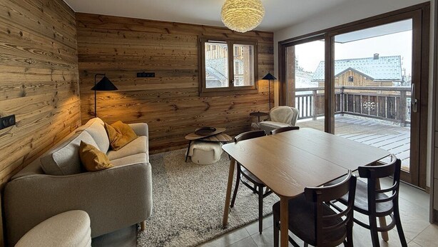 Una habitación acogedora con una pared de madera, un sofá, una mesa de comedor y vistas a un balcón.
