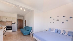 A bedroom with a bed, a sofa, and a kitchenette.
