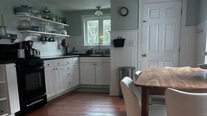 Une cuisine avec des meubles blancs, une table en bois et un fourneau.