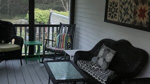 Une véranda avec un canapé en osier, une petite table et une chaise.