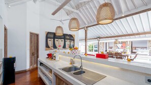 A modern kitchen with a large island, stainless steel sink, and pendant lighting. - Villa Yang Tao 4 (Seminyak)