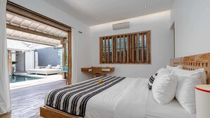 A bedroom with a bed, a desk, and a view of a pool. - Villa Yang Tao 4 (Seminyak)