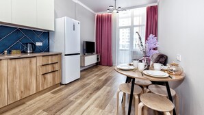 Une cuisine moderne avec des meubles en bois, un réfrigérateur blanc et un coin repas comprenant une table ronde et des tabourets.