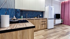 Une cuisine moderne avec des armoires en bois, un plan de travail noir, une cuisinière encastrée et un réfrigérateur blanc.