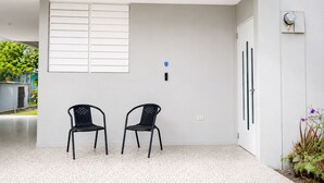 Una habitación moderna y limpia con dos sillas negras, una puerta blanca y un ventanal con persianas horizontales.