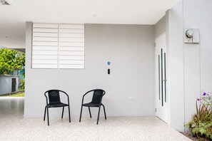 A clean, modern room with two black chairs, a white door, and a window with horizontal blinds.