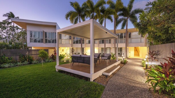 Een modern huis met een overdekt terras, een verzorgd gazon en een houten terras.