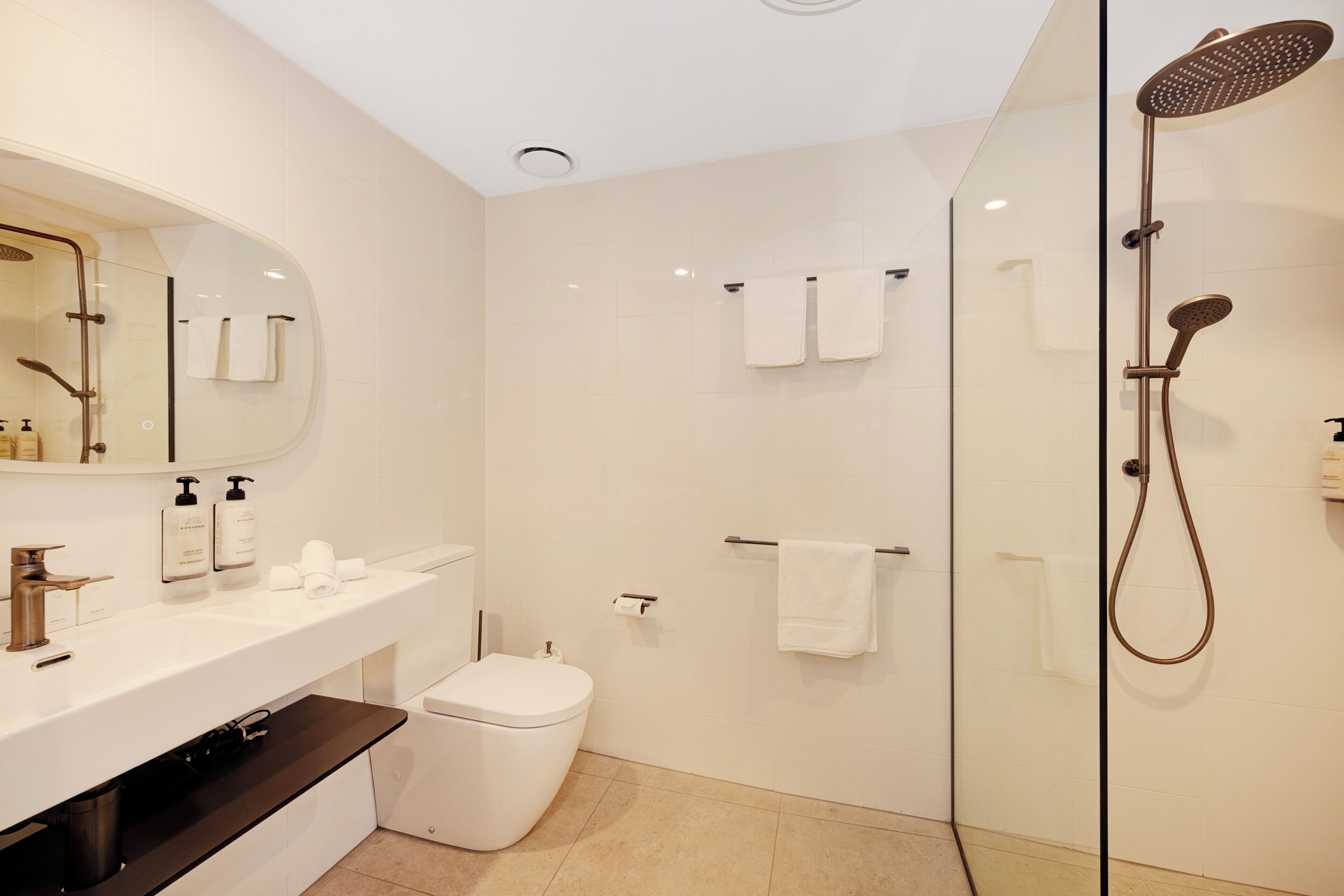 Ein modernes Badezimmer mit einer Duschkabine, einer weißen Toilette, einem Waschtisch mit Spiegel und einem Waschbecken.