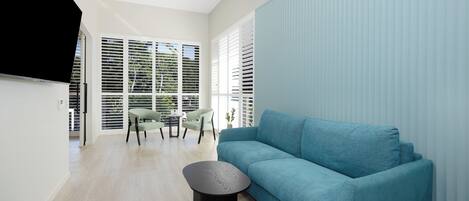 Un salon moderne avec un canapé bleu, une table basse ronde noire et un coin repas comprenant des chaises et une table.