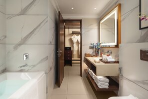 A modern bathroom with a marble floor, a bathtub, a vanity with a mirror, and a shower area. - Sarovar Portico Hanumangarh (Hanumangarh)