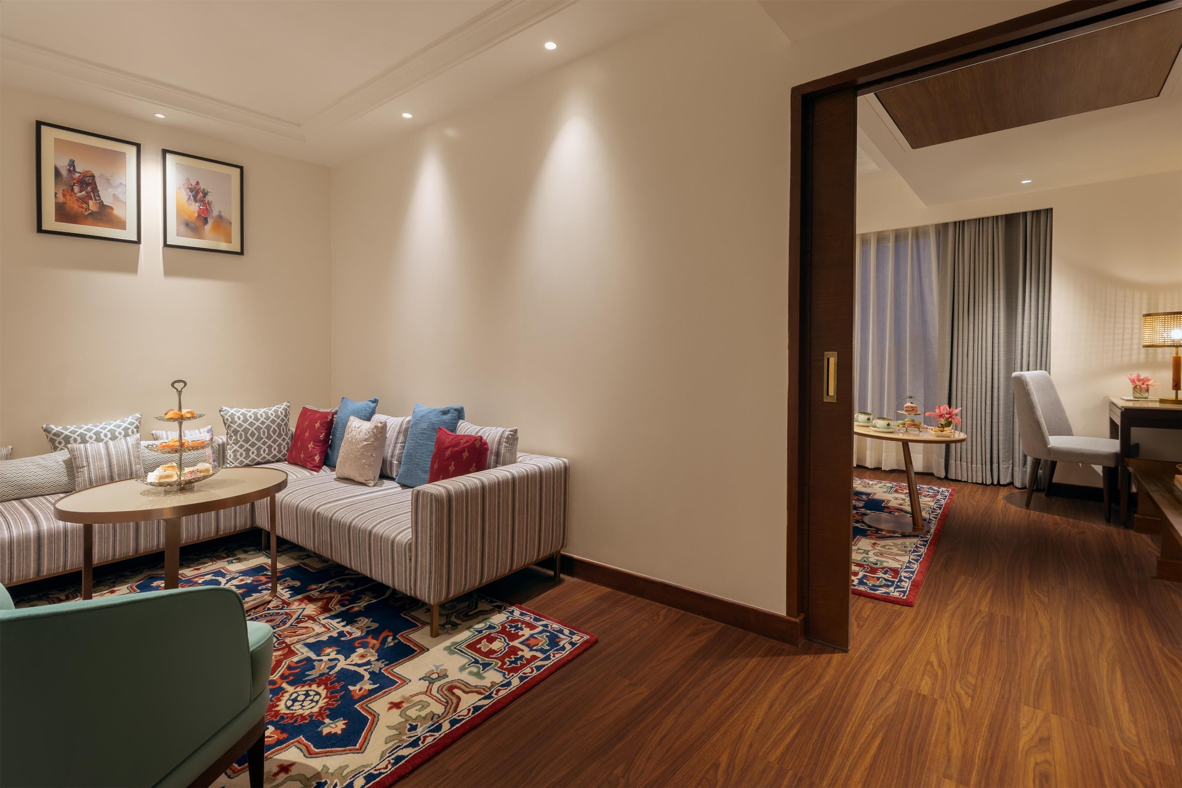 A modern hotel room with a striped sofa, a small round table, and a patterned rug.