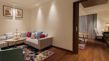 A modern hotel room with a striped sofa, a small round table, and a patterned rug.