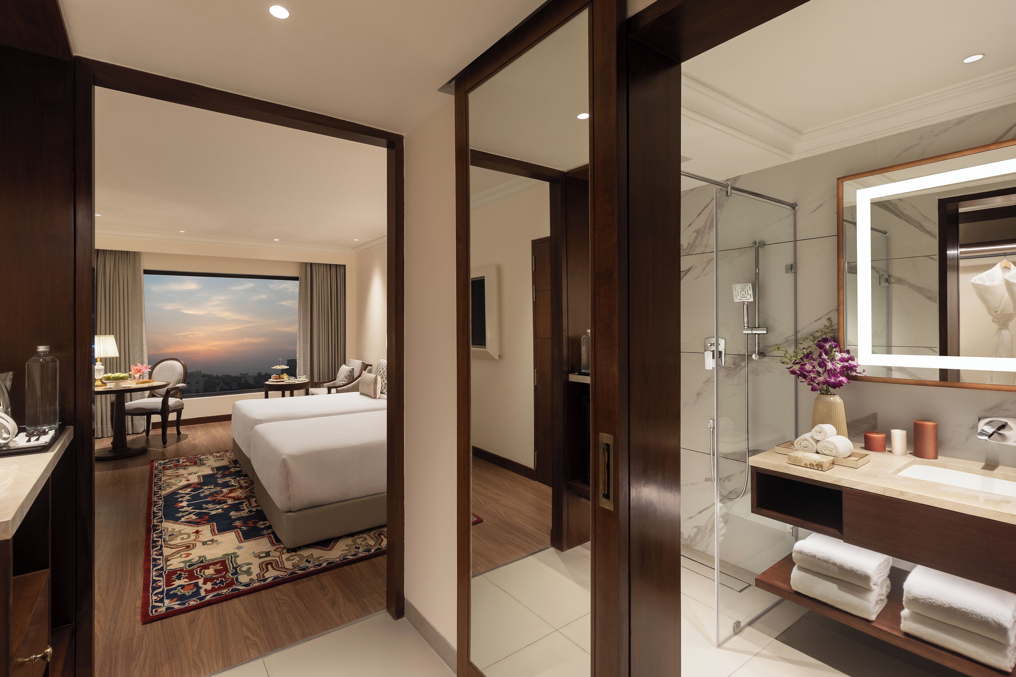 A hotel room with a bed, desk, chair, and a large window with a view.