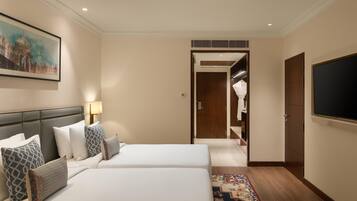 Habitación de hotel con dos camas, un televisor, un cuadro y un pasillo que conduce a un armario.