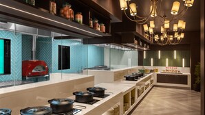 A modern kitchen with a red oven, glass-fronted cabinets, and a variety of cooking pots on the counter.