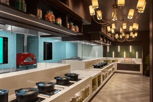Una cocina moderna con horno rojo, armarios con puertas de vidrio y una variedad de ollas en la encimera.
