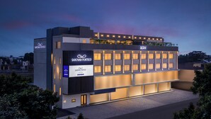 A modern hotel with a prominent Sarovar Portoico sign, multiple balconies, and a well-lit facade.