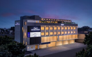 Un hotel moderno con un llamativo letrero Sarovar Portoico, varios balcones y una fachada bien iluminada.