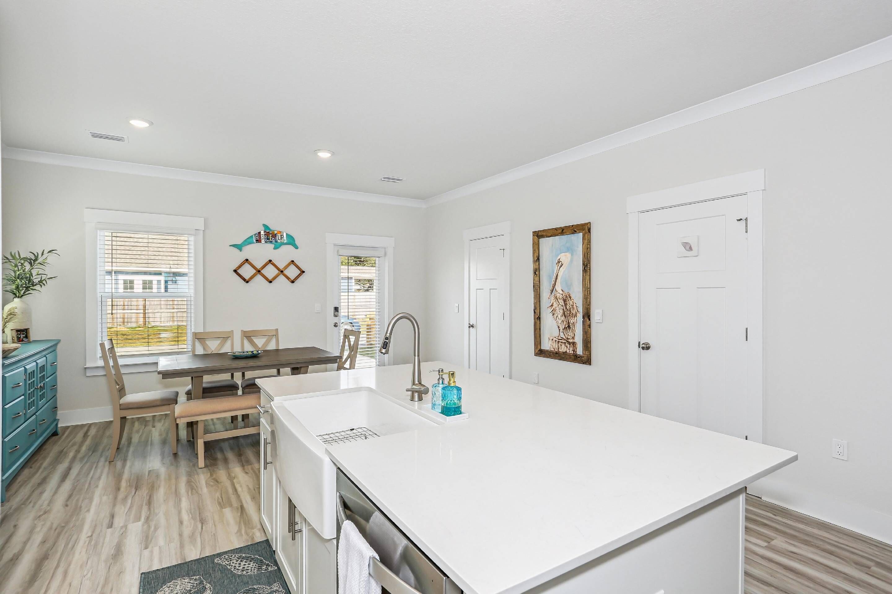 A modern kitchen with a large island, white cabinetry, and a dining area with a table and chairs.
