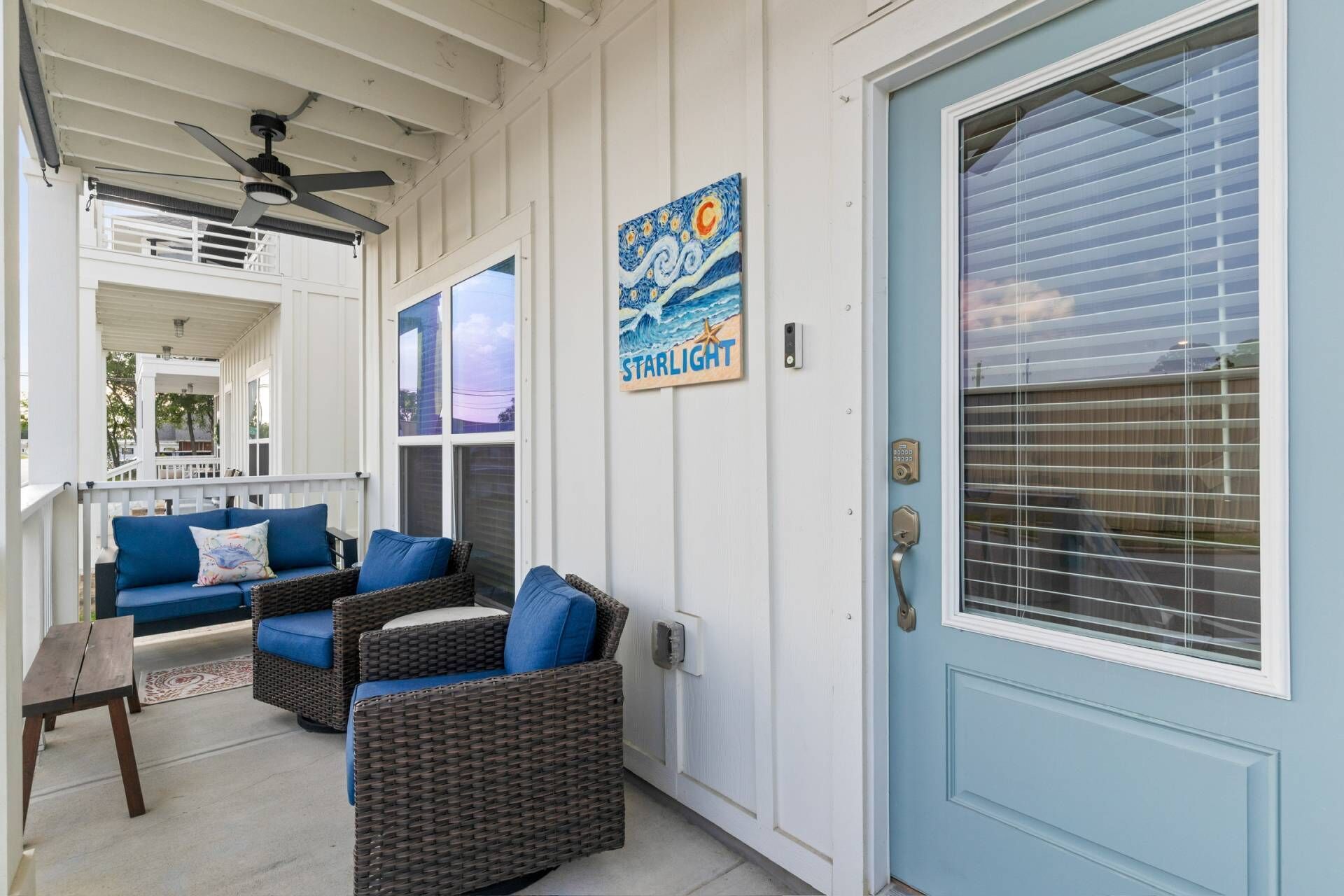 A porch with wicker furniture, a ceiling fan, and a door with a window.