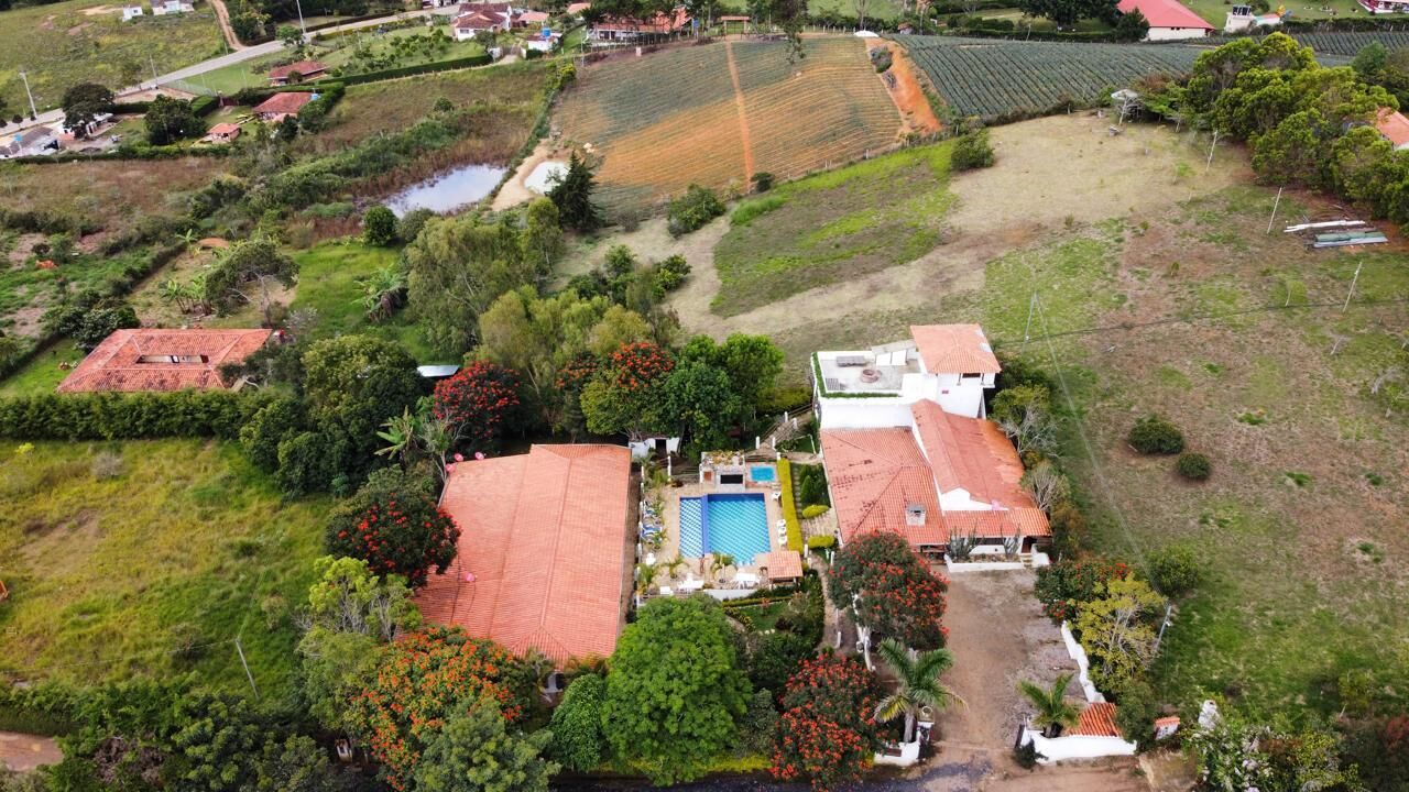 An aerial view of a residential area with houses, a swimming pool, and surrounding greenery.